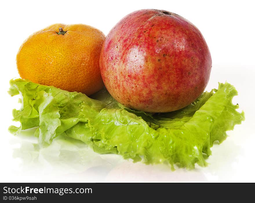 Bright tangerine and grapefruit on the green leaf lettuce isolated on white background. Bright tangerine and grapefruit on the green leaf lettuce isolated on white background