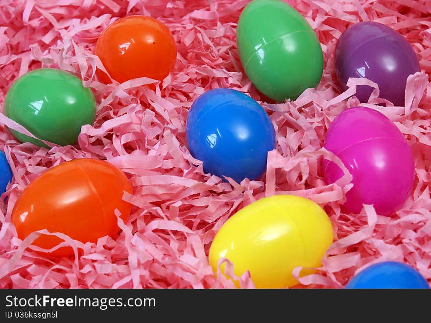 A variety of plastic Easter eggs on pink paper shreds.