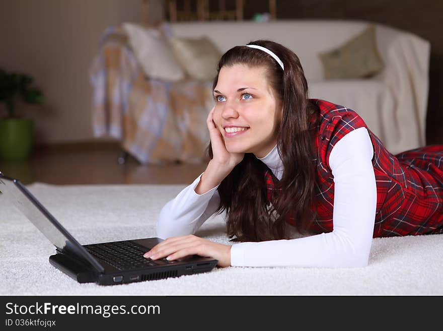 A young girl with a lap top at home on the floor of a living room