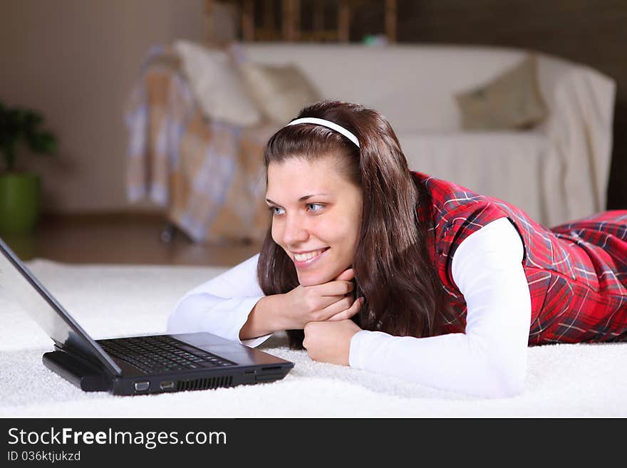 A young girl with a lap top at home on the floor of a living room