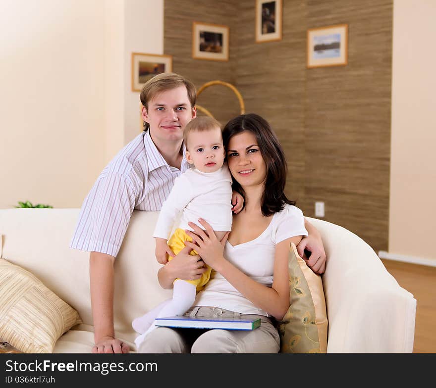 Young happy family playing with a baby in the living-room. Young happy family playing with a baby in the living-room