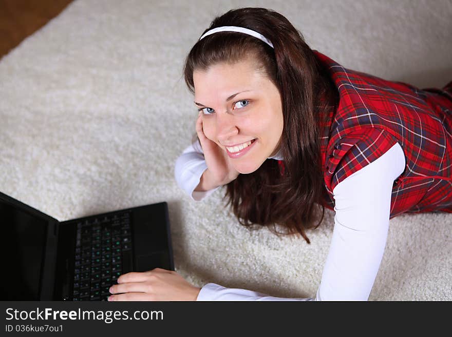 A young girl with a lap top at home on the floor of a living room