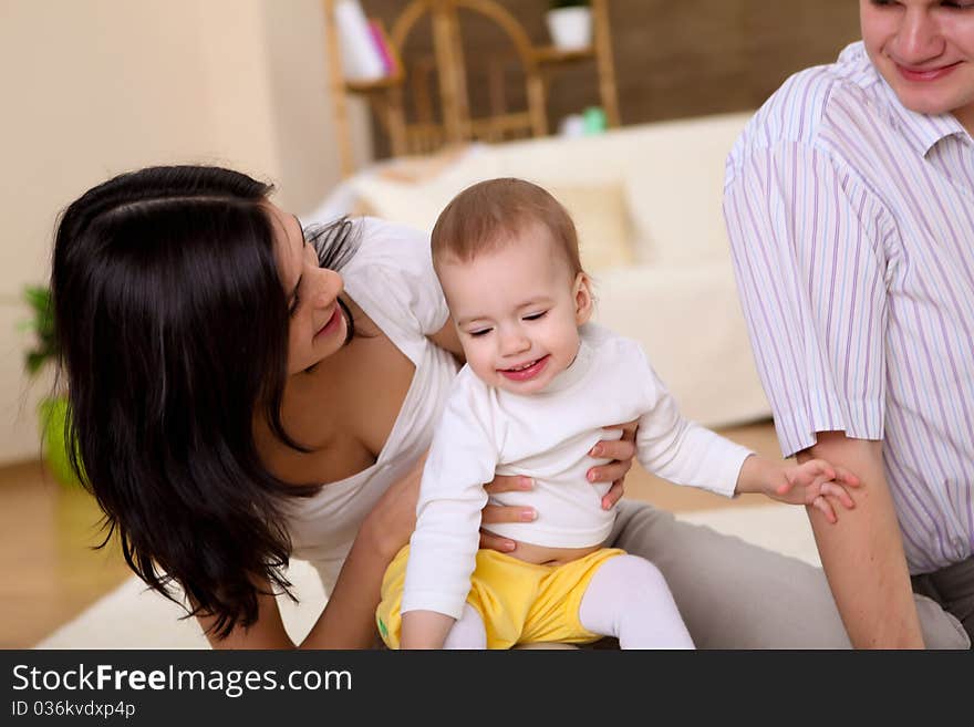 Young happy family playing with a baby in the living-room. Young happy family playing with a baby in the living-room