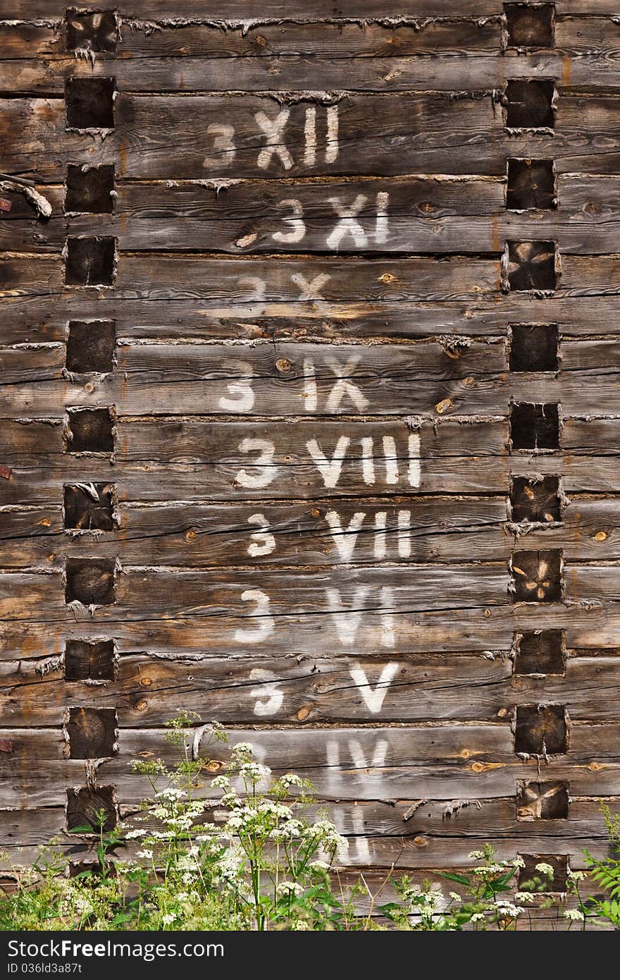 Wooden wall with written arabic and roman numbers in logs in order. Wooden wall with written arabic and roman numbers in logs in order