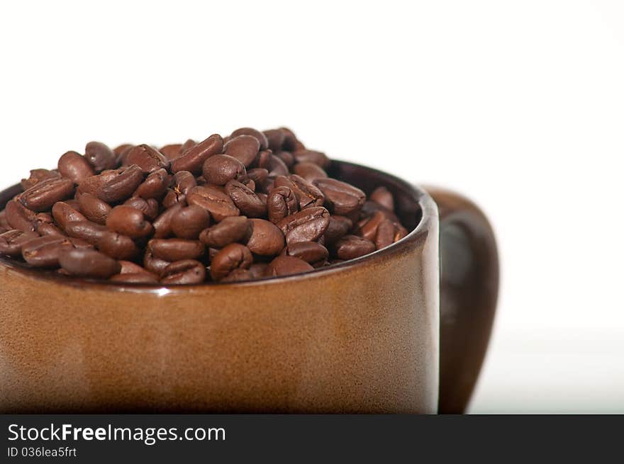 Still life close up of roasted coffee beans in a brown earthenware mug. Still life close up of roasted coffee beans in a brown earthenware mug