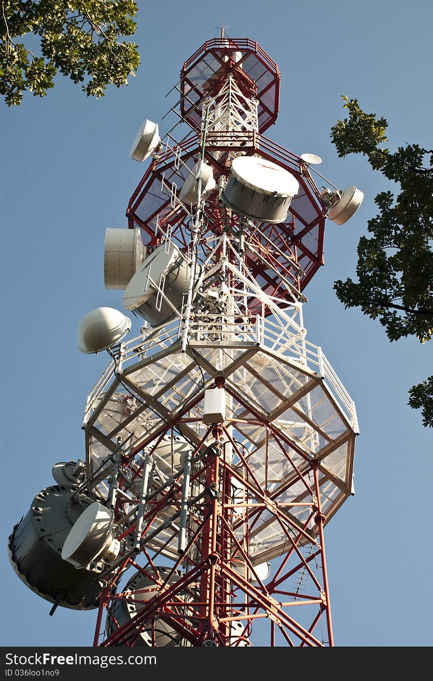 Huge communication antenna tower and satellite dishes against blue sky. Huge communication antenna tower and satellite dishes against blue sky