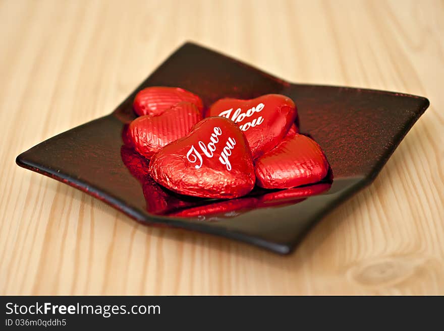 On the table in bright red decorative plates loose chocolates. On the table in bright red decorative plates loose chocolates.