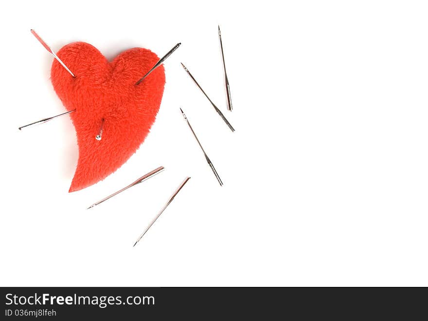 Red heart and the sewing needles, is isolated on a white background. Red heart and the sewing needles, is isolated on a white background