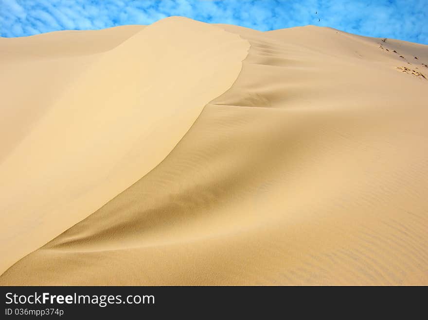 On the photo:Dunes on the background of the blue sky