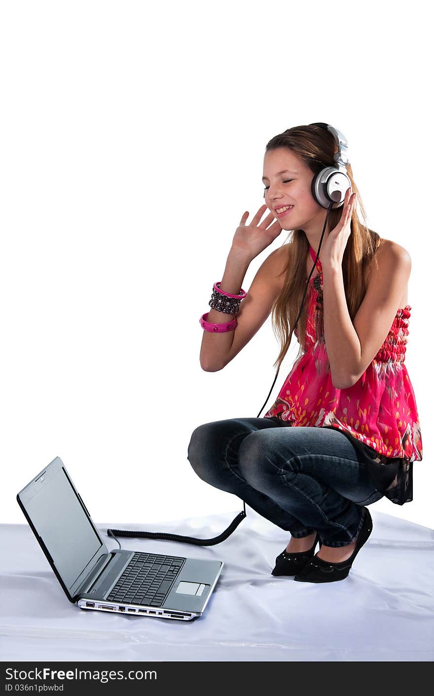 The cheerful girl in ear-phones and with the laptop listens to music. The cheerful girl in ear-phones and with the laptop listens to music