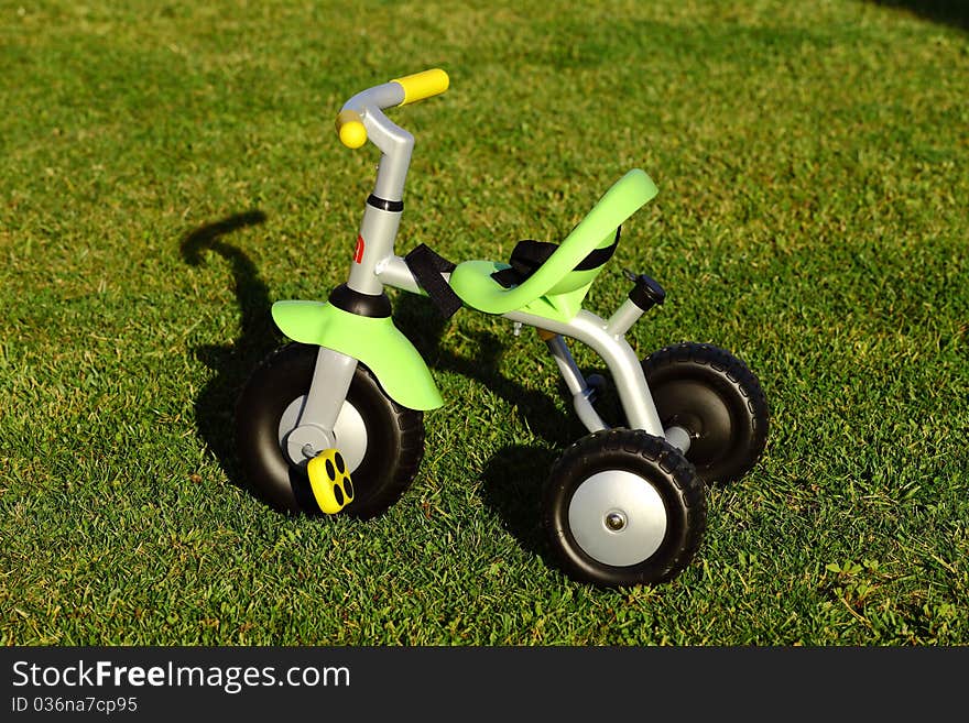 Children tricycle in a green garden. Children tricycle in a green garden