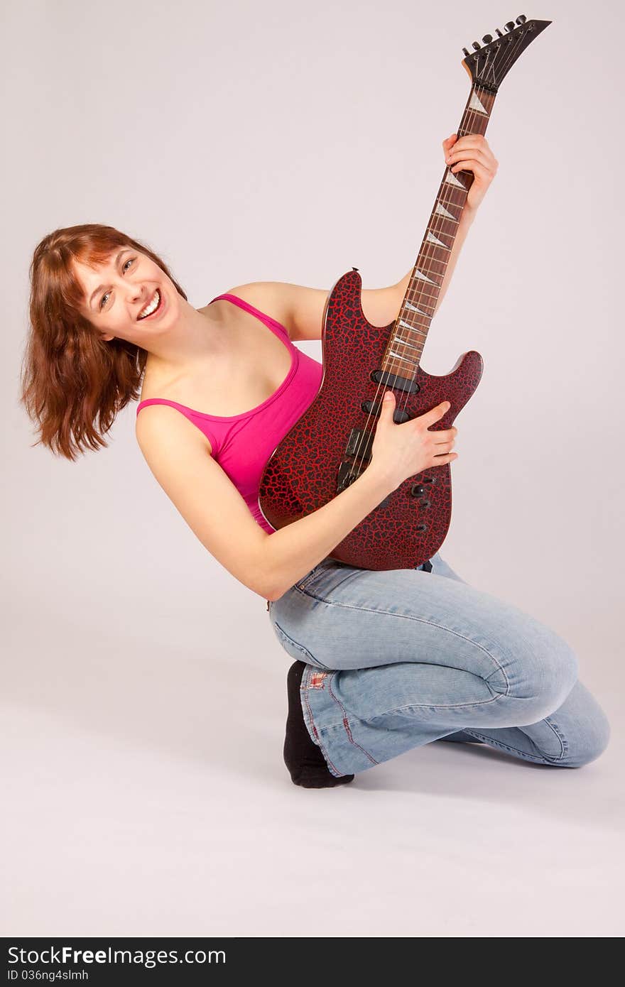 A beautiful young woman is playing a guitar. A beautiful young woman is playing a guitar