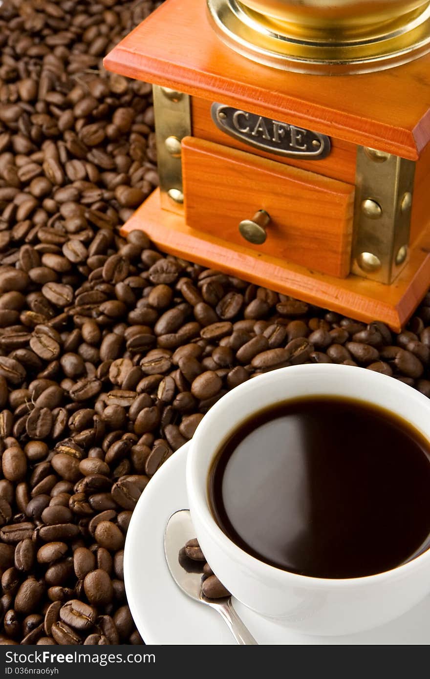 Cup of coffee and gold grinder on beans