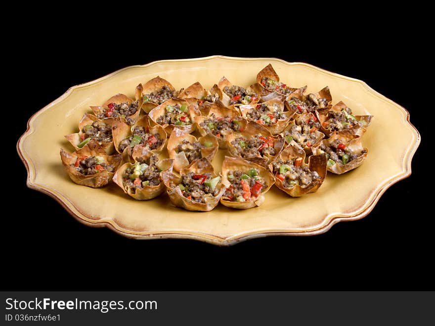 A platter of won ton appetizers on a black background. A platter of won ton appetizers on a black background