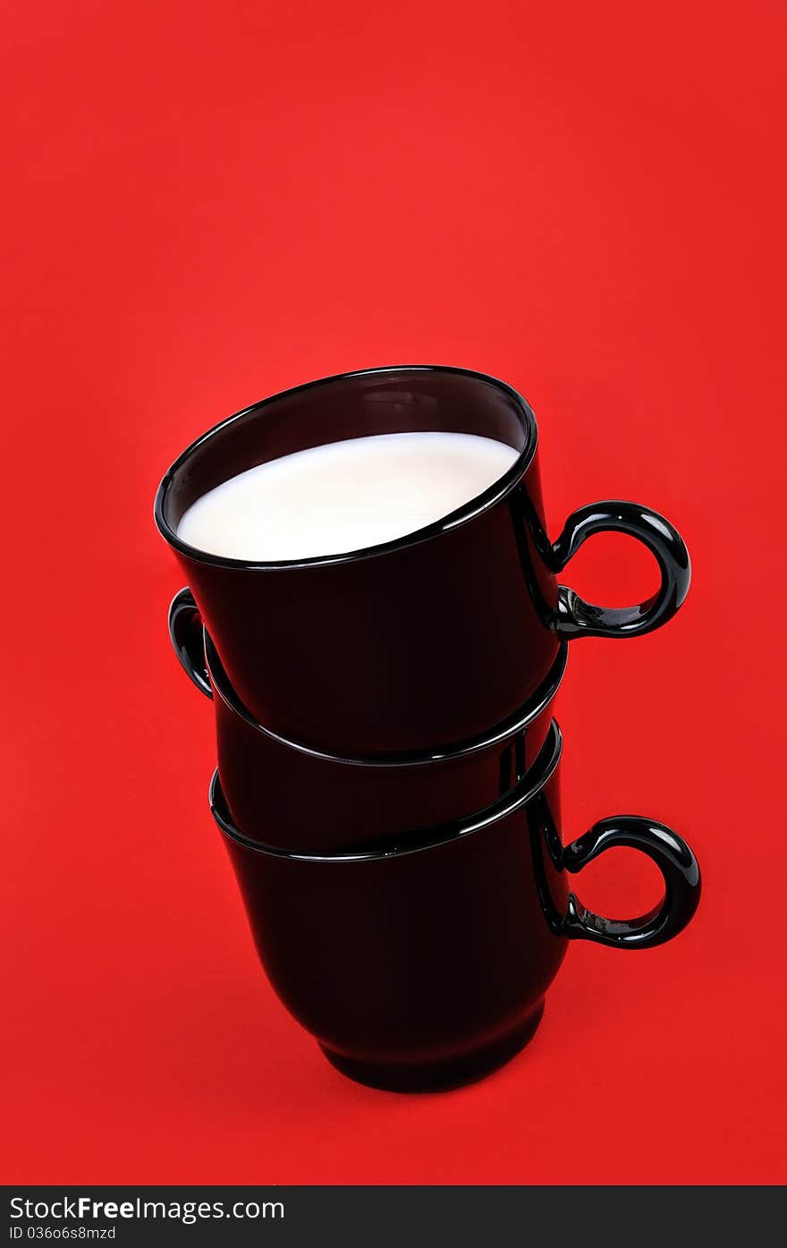 Cups with milk on a red background