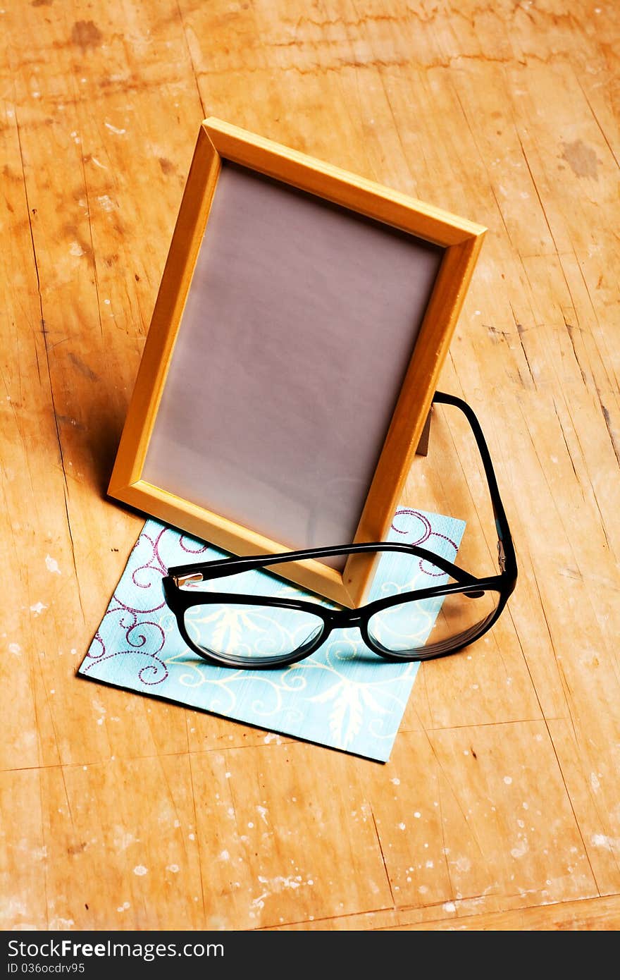 Modern photoframe with glasses on wooden background