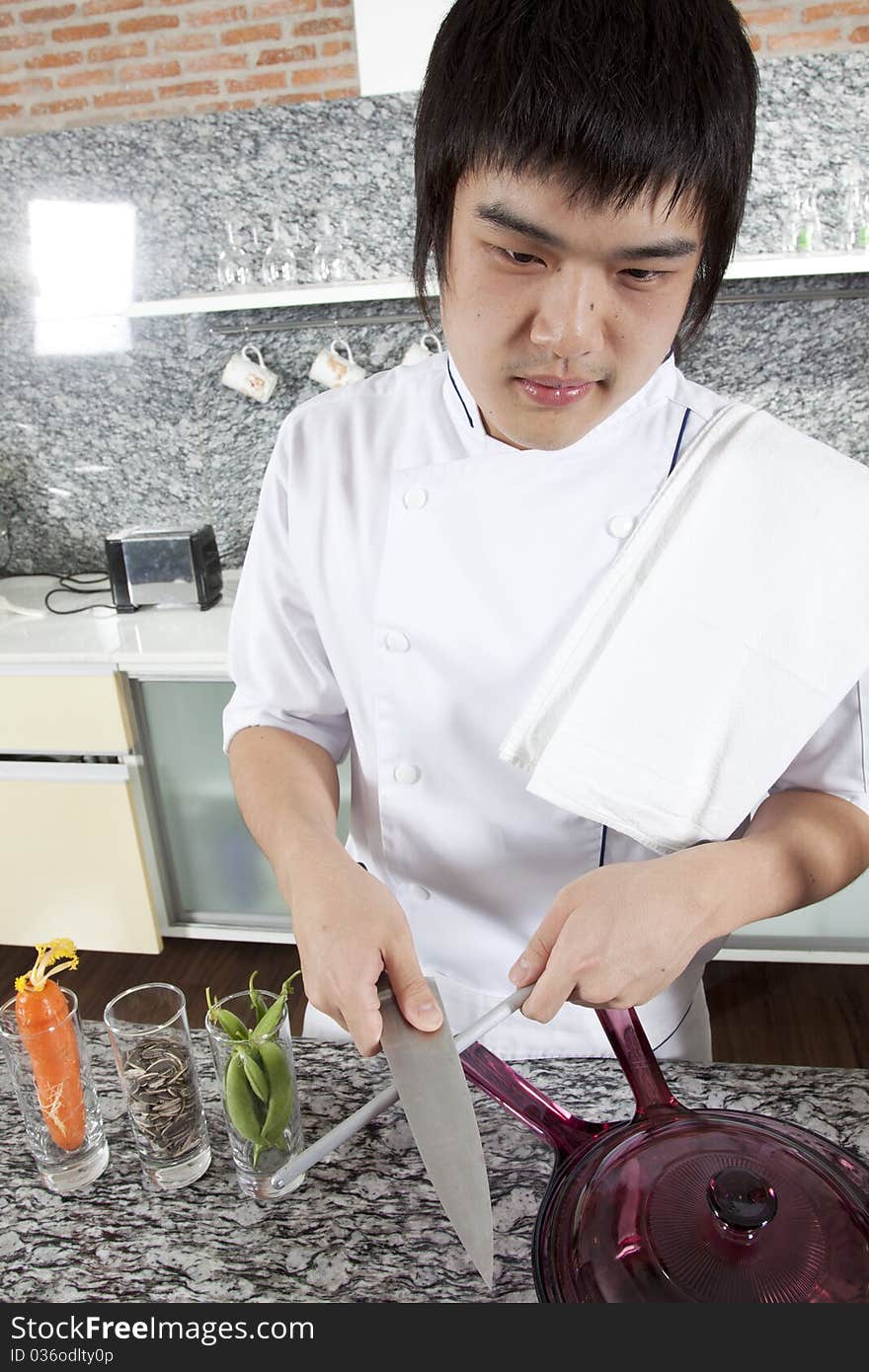 Asian young chef sharpening a knife brutally.