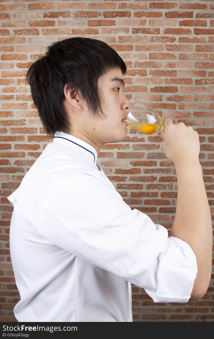 Asian young chef about to drink raw egg. Asian young chef about to drink raw egg.