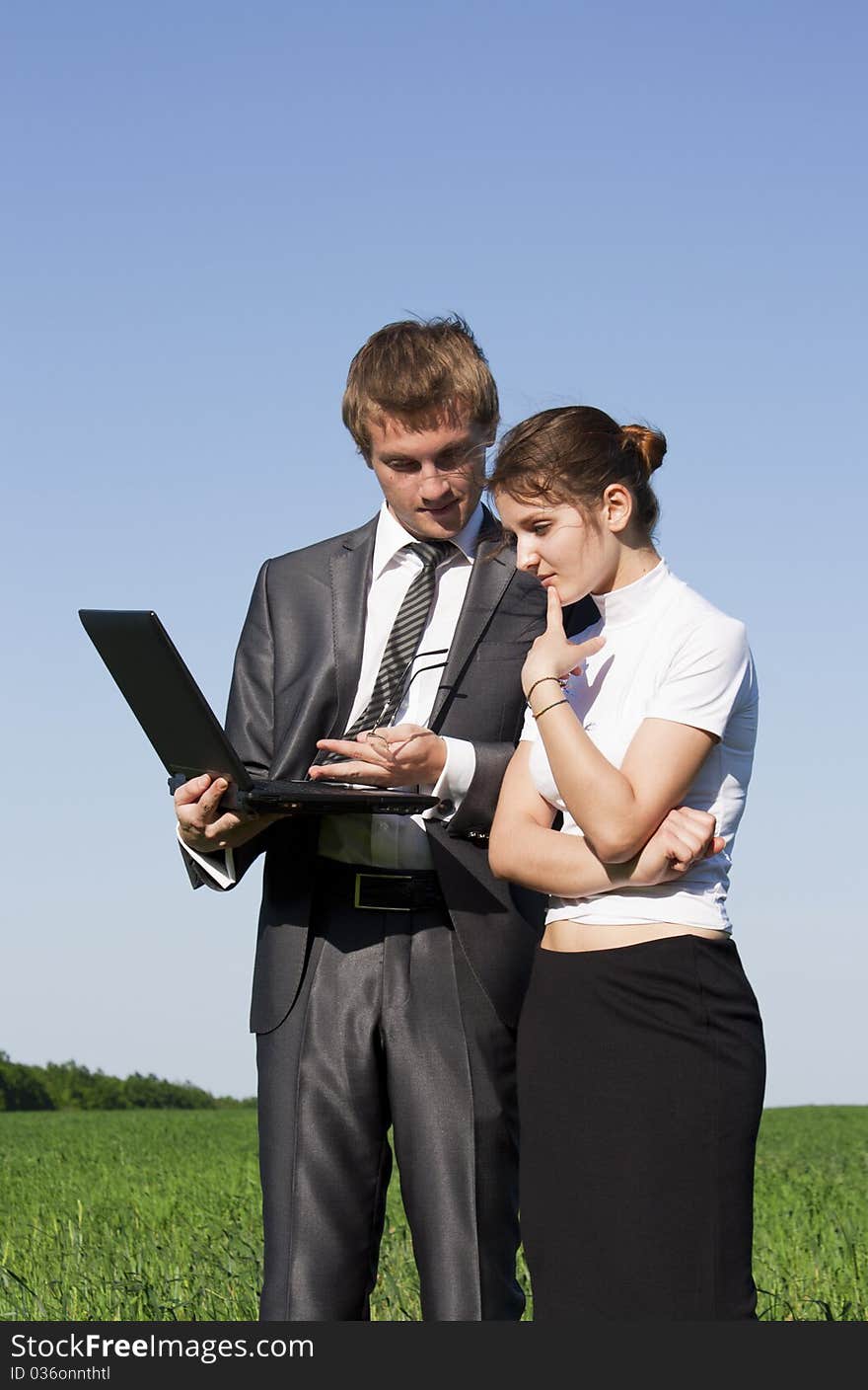 Two successful workers in the street with a laptop