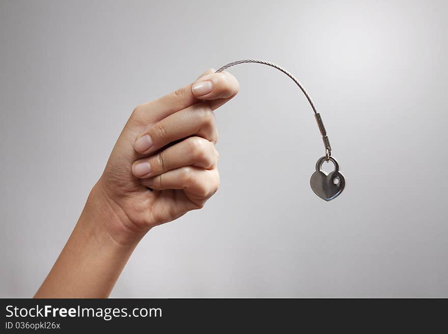 A hand holding a heart shape key-chain acting fishing. A hand holding a heart shape key-chain acting fishing.