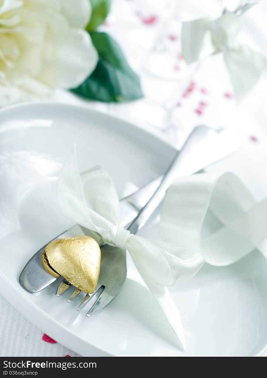 Fork and knife laying on plate with ribbon and heart. Fork and knife laying on plate with ribbon and heart