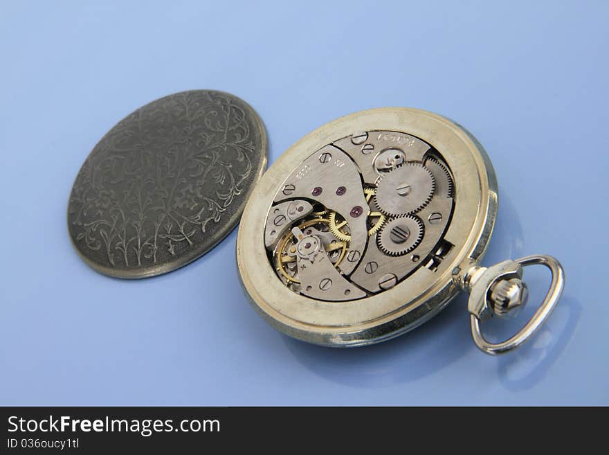 Clockwork pocket watch on the light blue background. Clockwork pocket watch on the light blue background