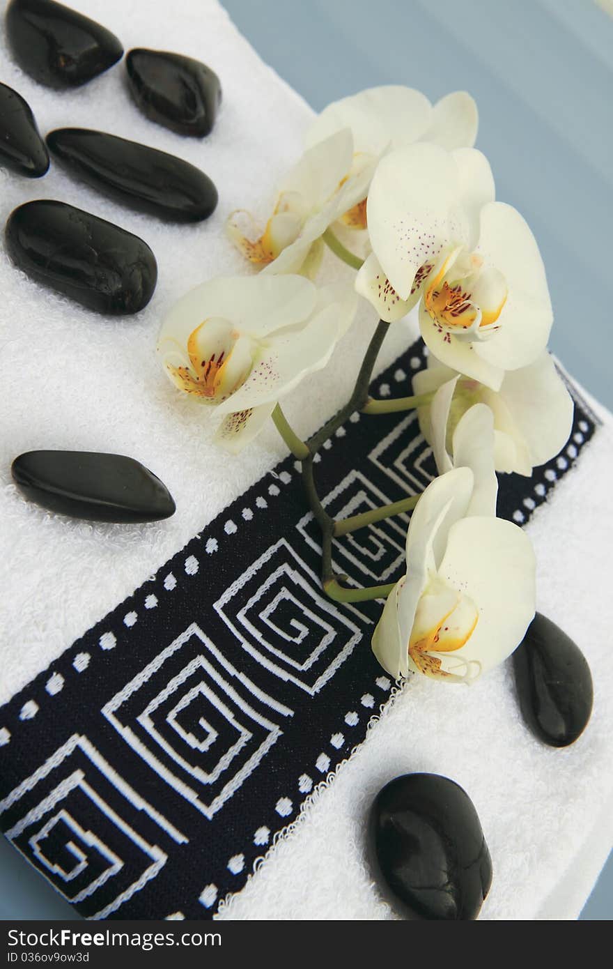 Massage stones, orchid and a black-white towel. Massage stones, orchid and a black-white towel.