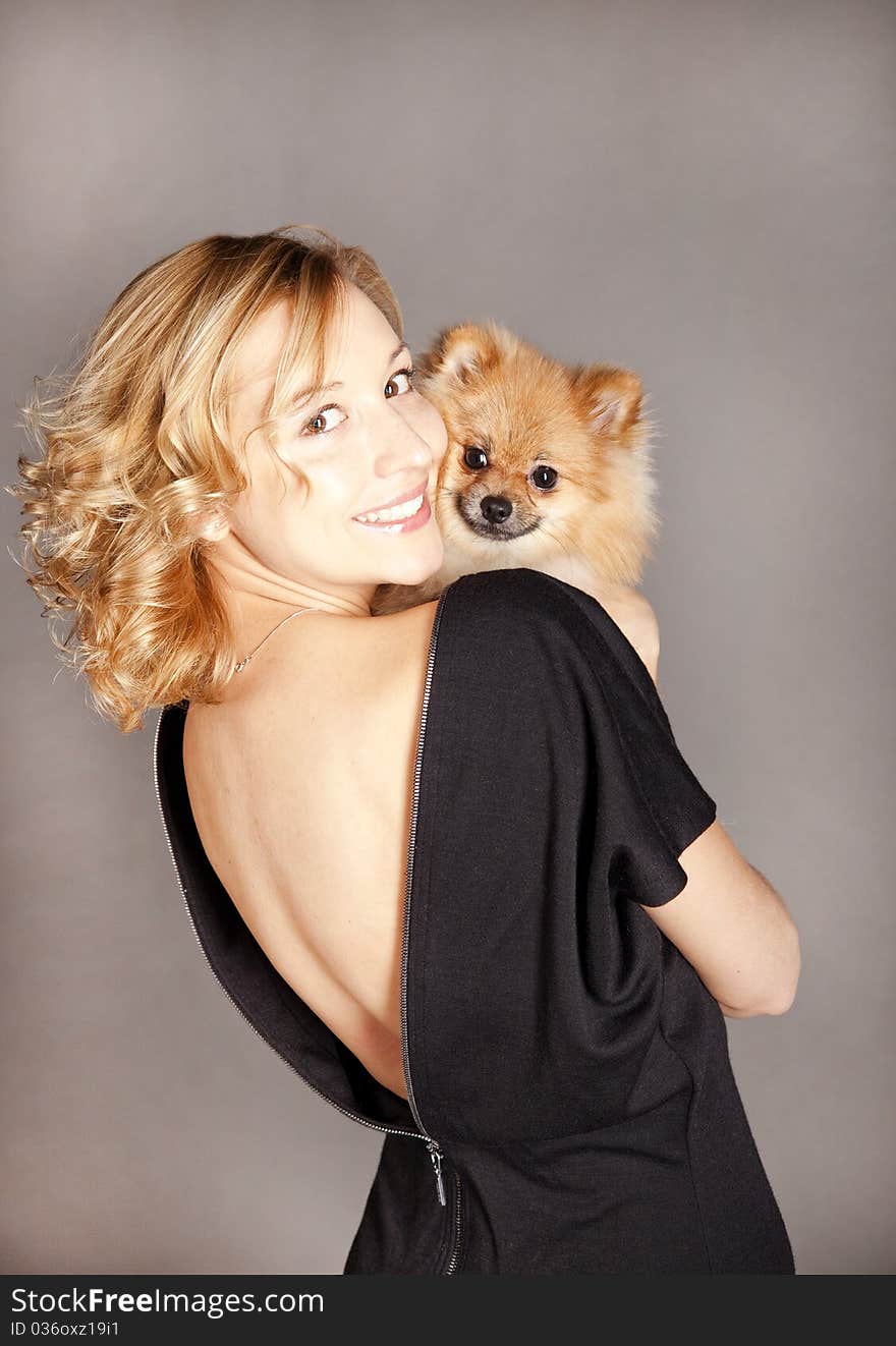 Girl holding a small dog on a gray background