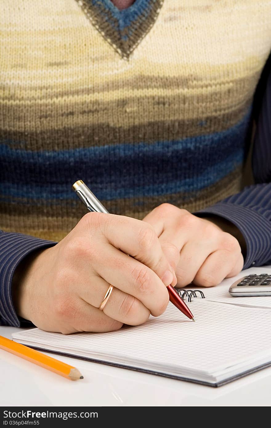 Male hand writing by pen on checked notebook. Male hand writing by pen on checked notebook