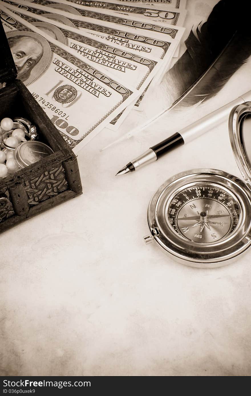 Dollar, pen and feather at table on sepia