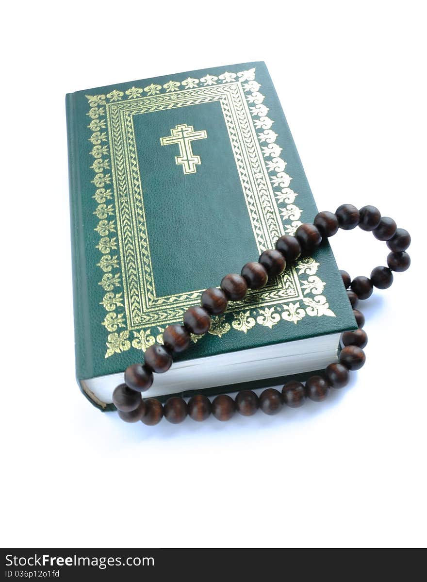 Closing bible of the green colour with gold(en) ornament and rosary beads overhand. Closing bible of the green colour with gold(en) ornament and rosary beads overhand