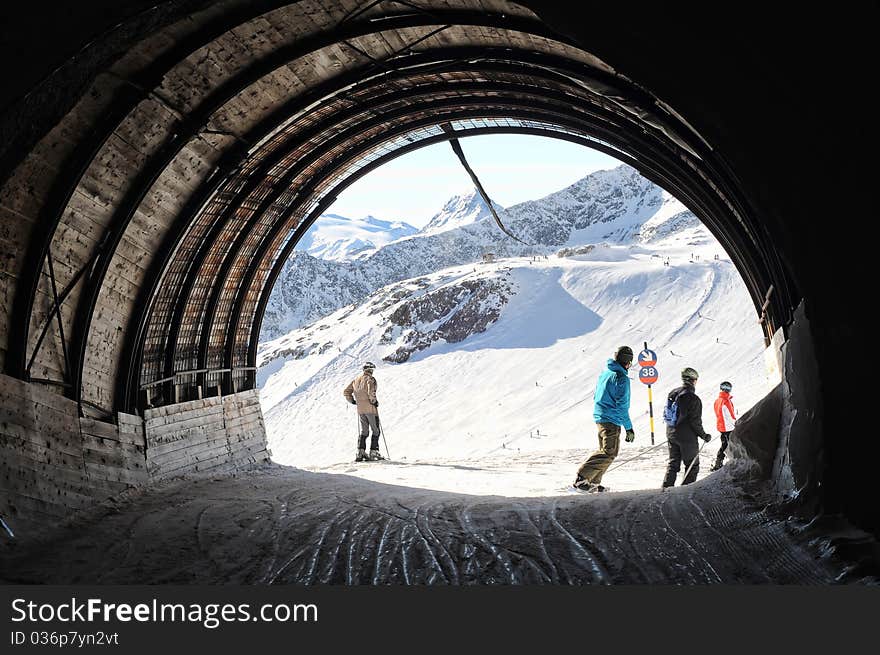 Skiers and snowboarders going out of tunnel connecting two sides of mountain. Skiers and snowboarders going out of tunnel connecting two sides of mountain.