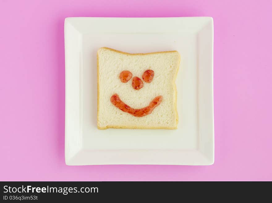 Strawberry jam painted as a smiling face on a bread. Strawberry jam painted as a smiling face on a bread