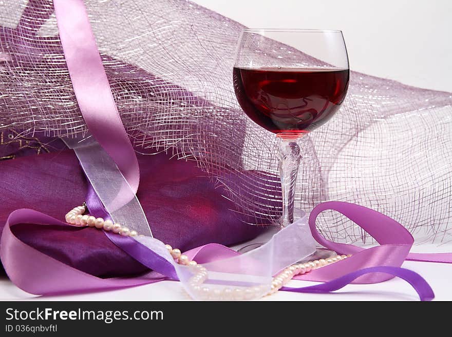 Glass with red wine on luxury background with beads and ribbons. Glass with red wine on luxury background with beads and ribbons