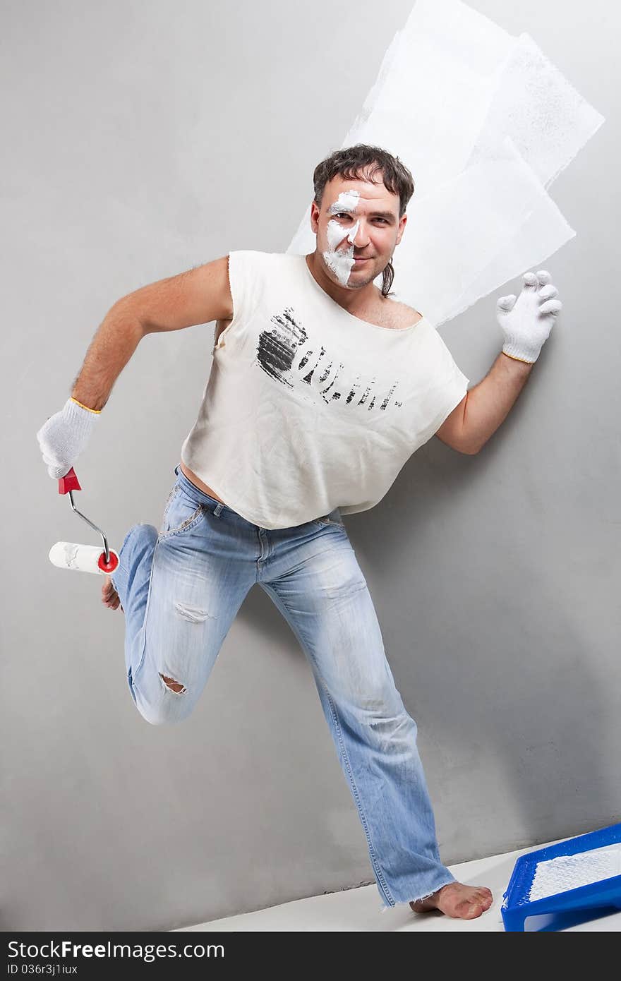 Cheerful worker painting a wall with roller