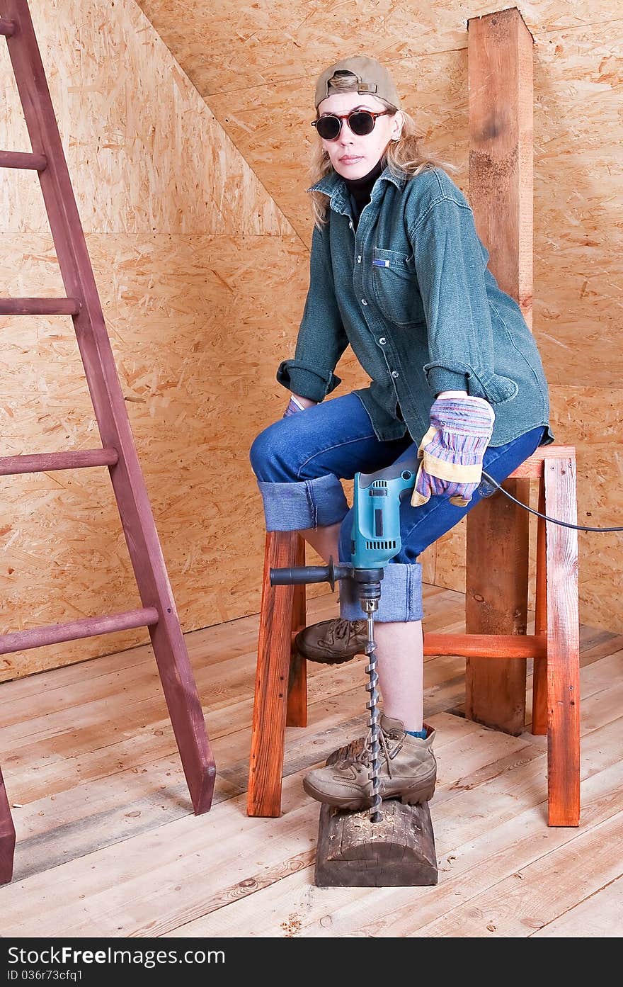 Female construction worker in a hard hat and tool belt with a cordless screwgun