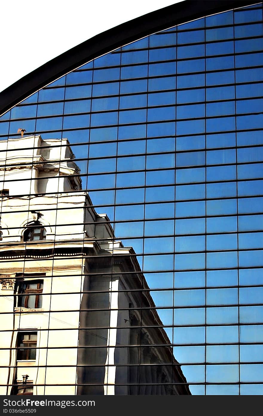 Old historical building reflected in a glass office building