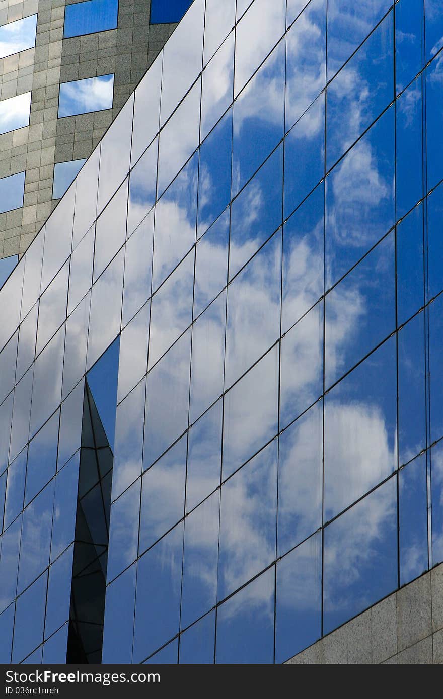 Detail of a modern office building with clouds reflection