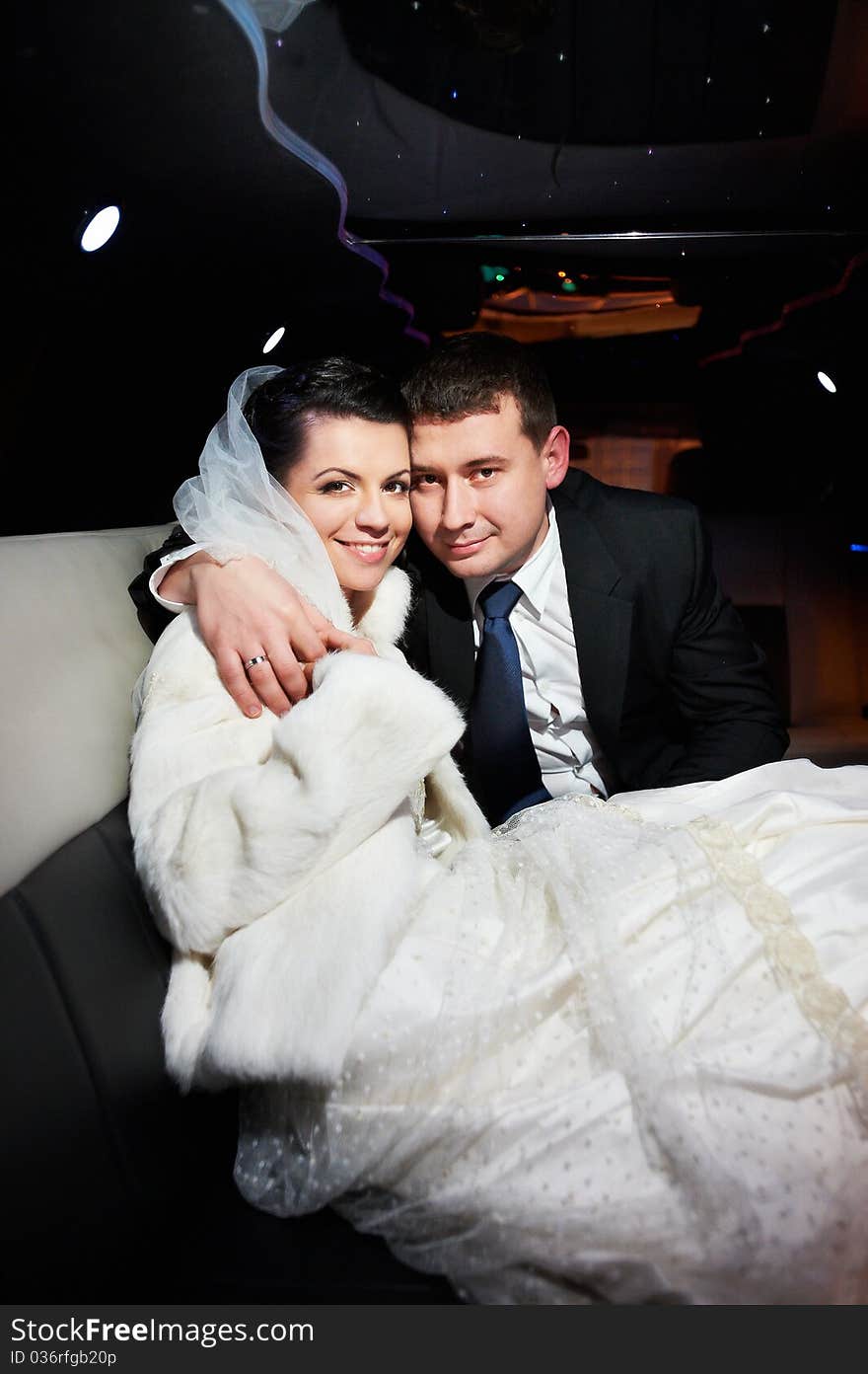 Elegant bride and groom in a wedding limousine