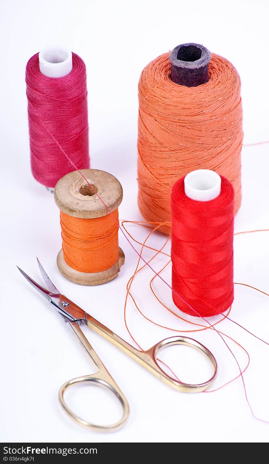 Spool of thread and scissors on white background.