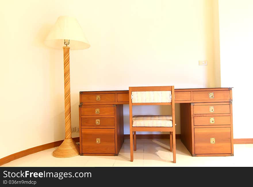 Detail of a wooden bedside table with three drawers and reading lamp