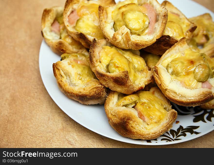 Close-up cakes made of puff pastry, sausages, pickles and cheese