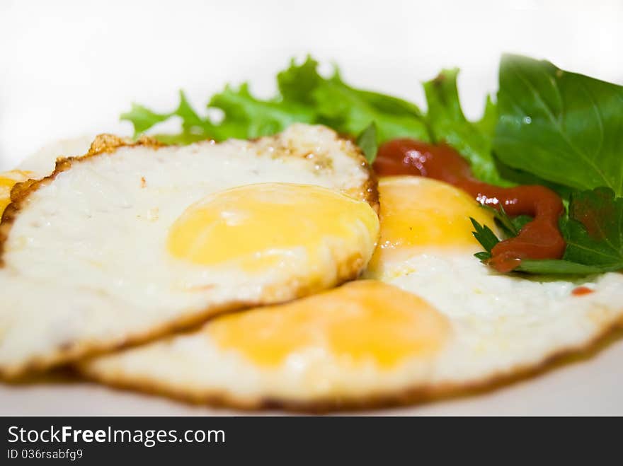 Fried tasty fried eggs with leaf salad on breakfast