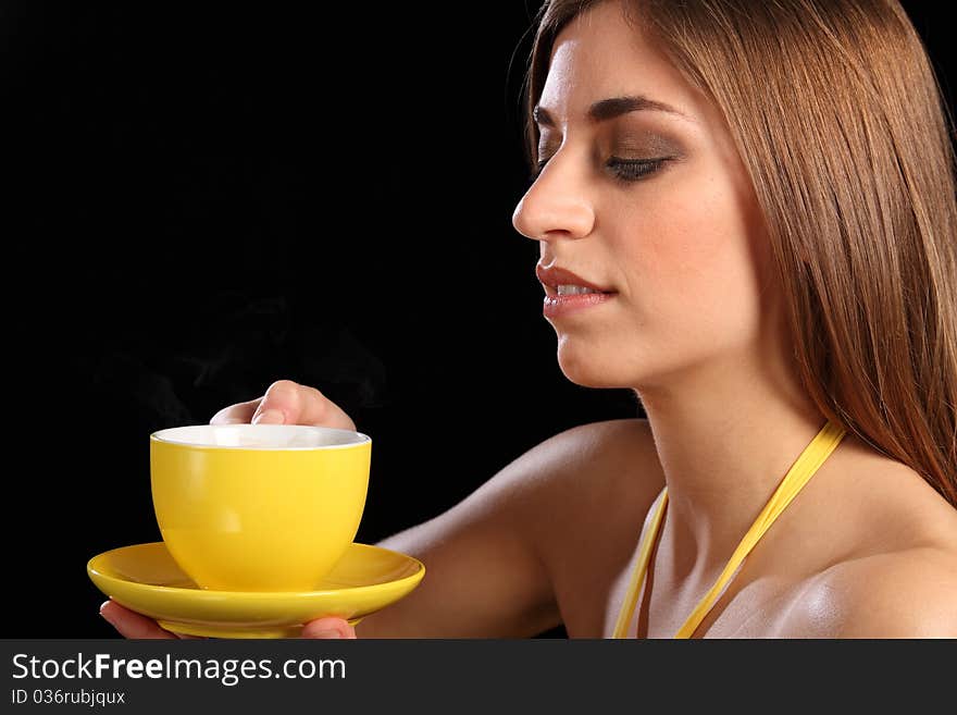 Headshot of beautiful young caucasion woman in holding yellow cup of tea up to her face, getting ready to drink. Headshot of beautiful young caucasion woman in holding yellow cup of tea up to her face, getting ready to drink.