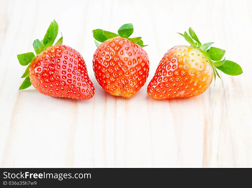 Three fresh strawberry on the wood.