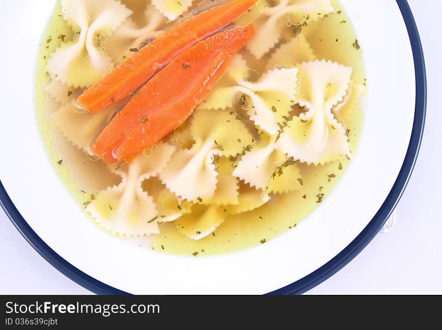 Chicken soup with farfalle pasta and carrots on a plate