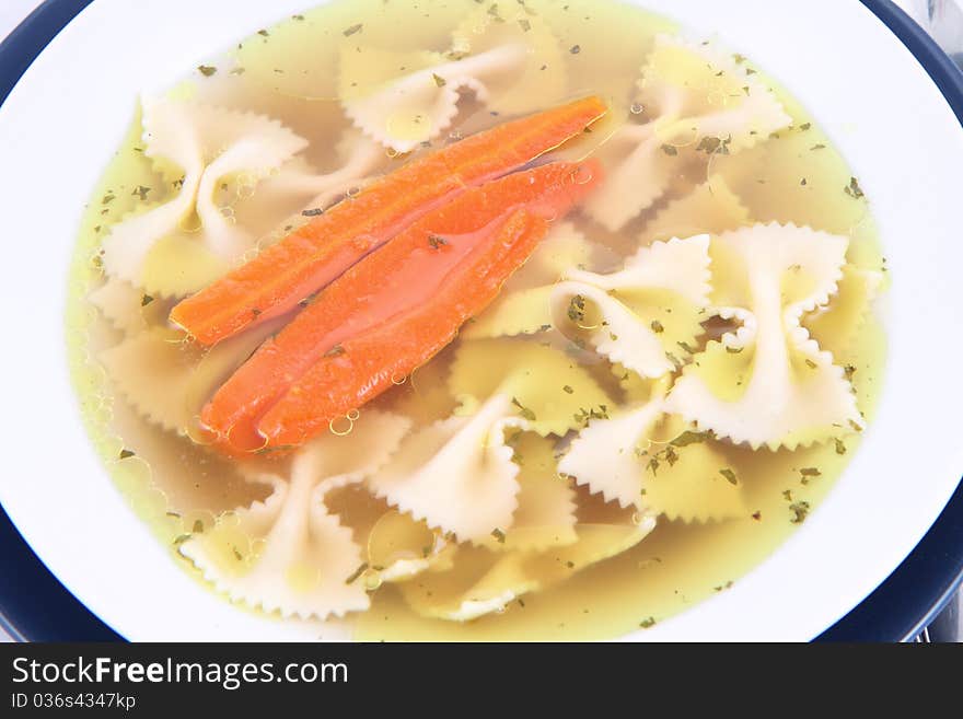 Chicken soup with farfalle pasta and carrots on a plate