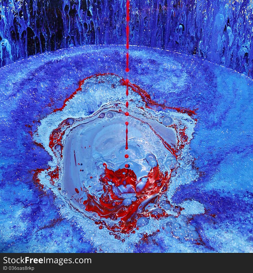 Flow of red paint falls into a bucket