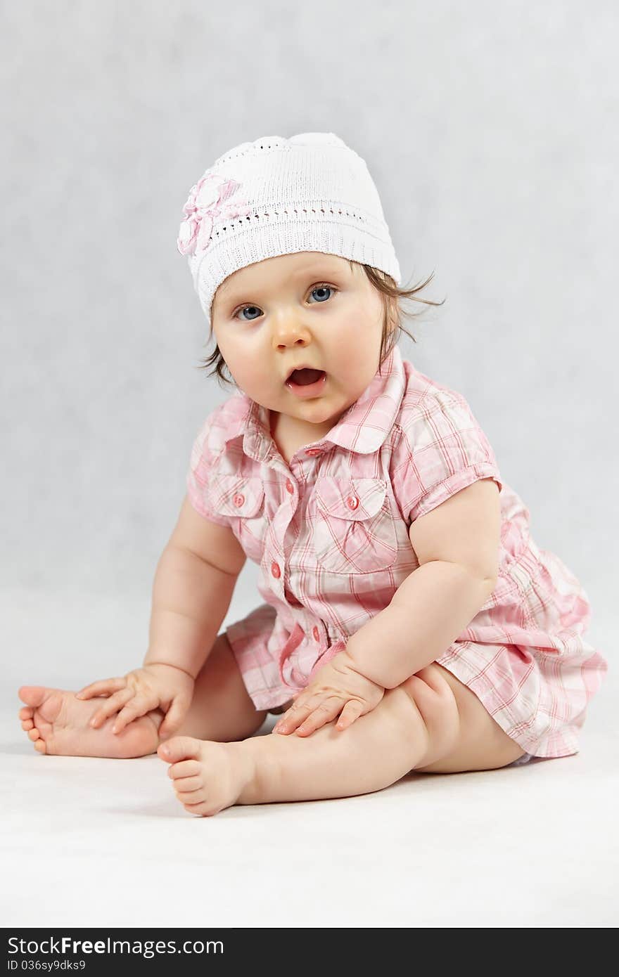 Sitting sweet baby in white cap - studio shot