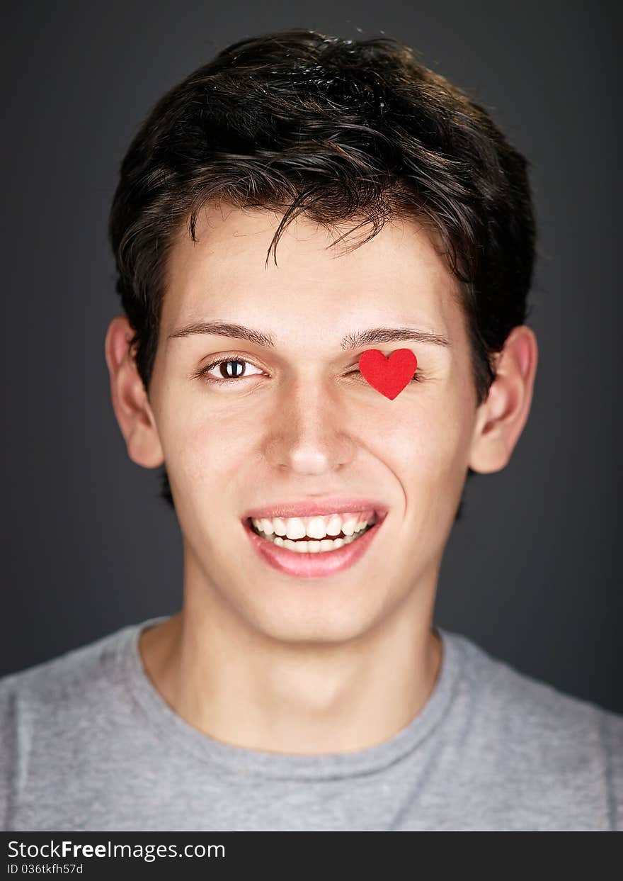 smiling man with small red heart on eye. smiling man with small red heart on eye